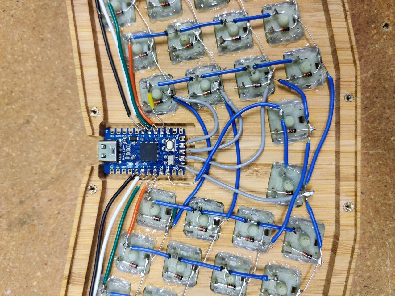 Hands assembling a compact mechanical keyboard at a workbench